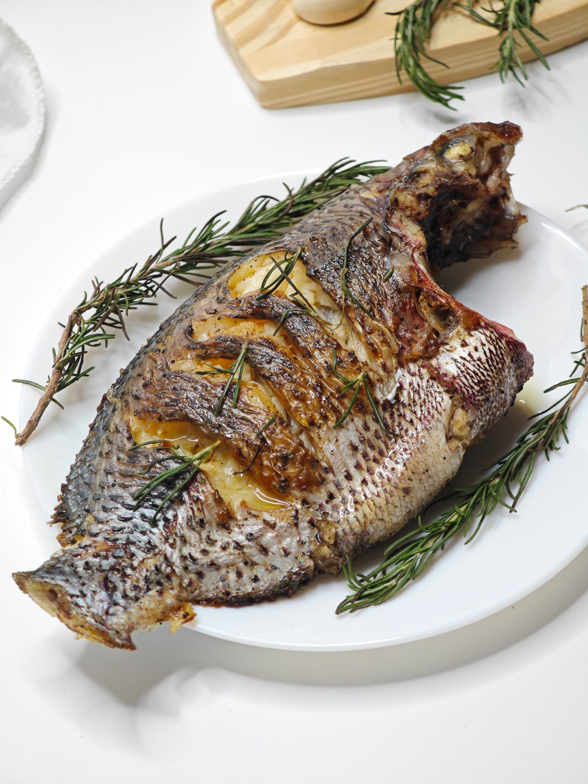 Peixe inteiro grelhado servido com ramos de alecrim fresco
