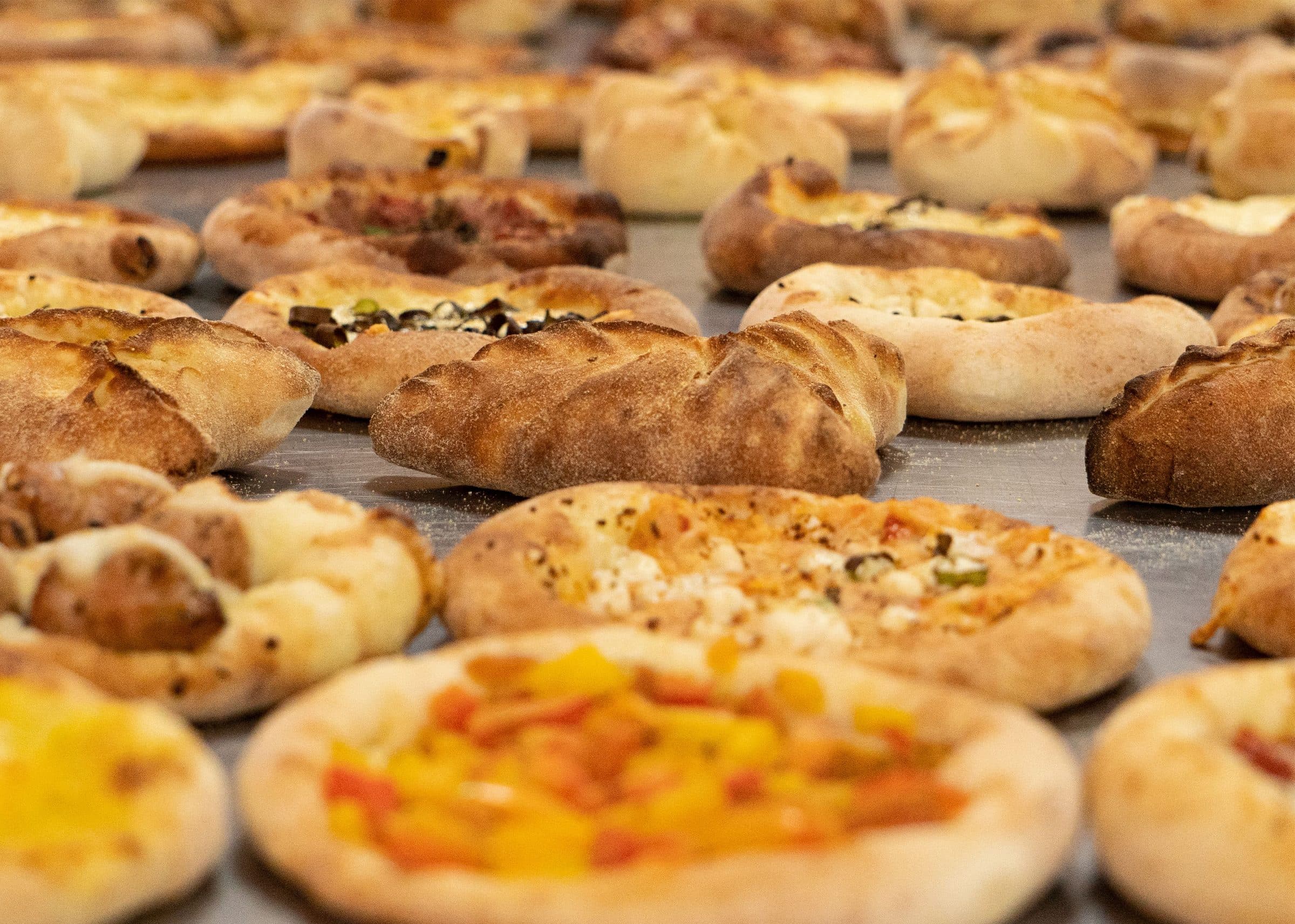 Variedade de doces e folhados assados com diferentes coberturas dispostos em uma bandeja de prata