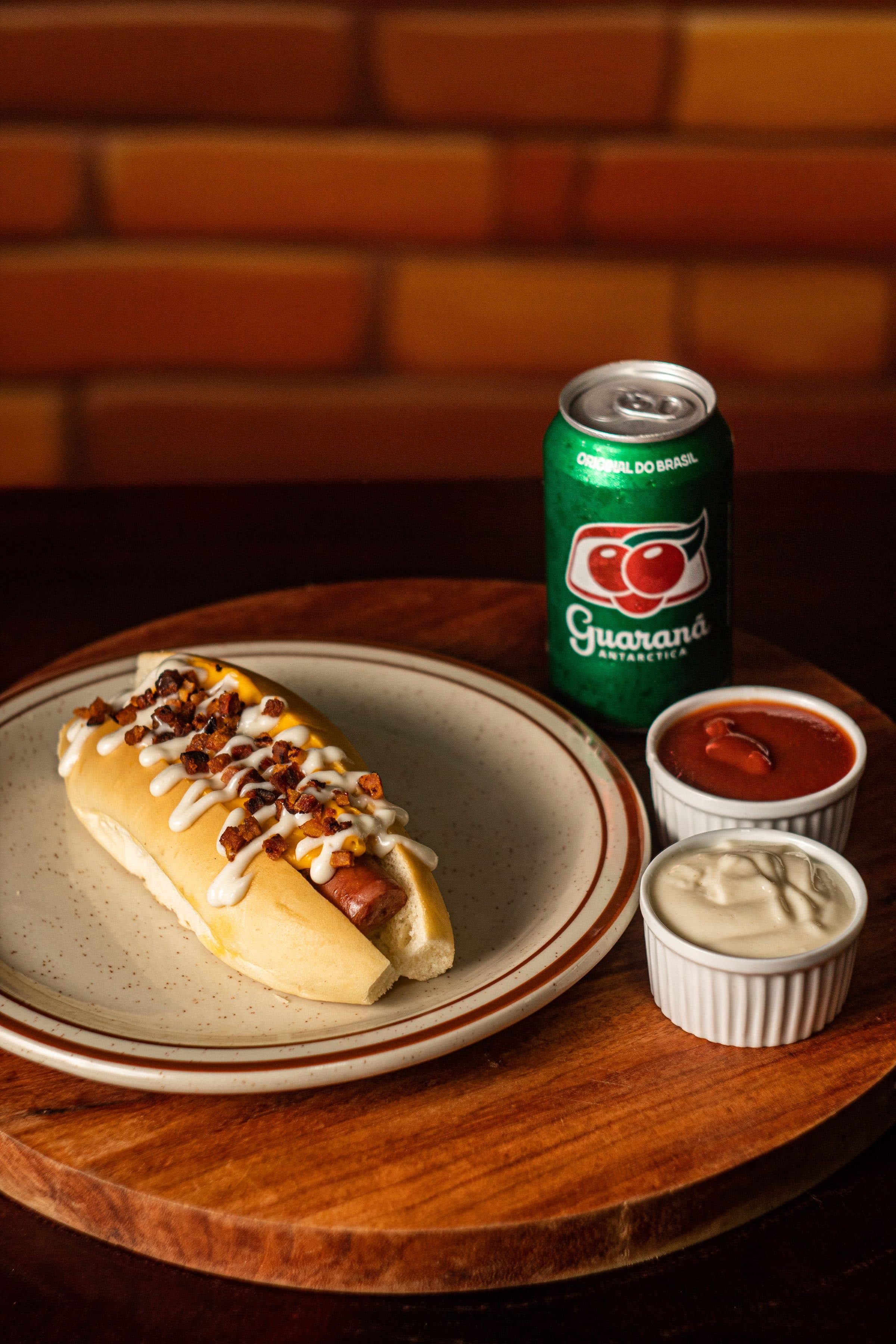 Cachorro-quente com coberturas servido com refrigerante e potes de molho