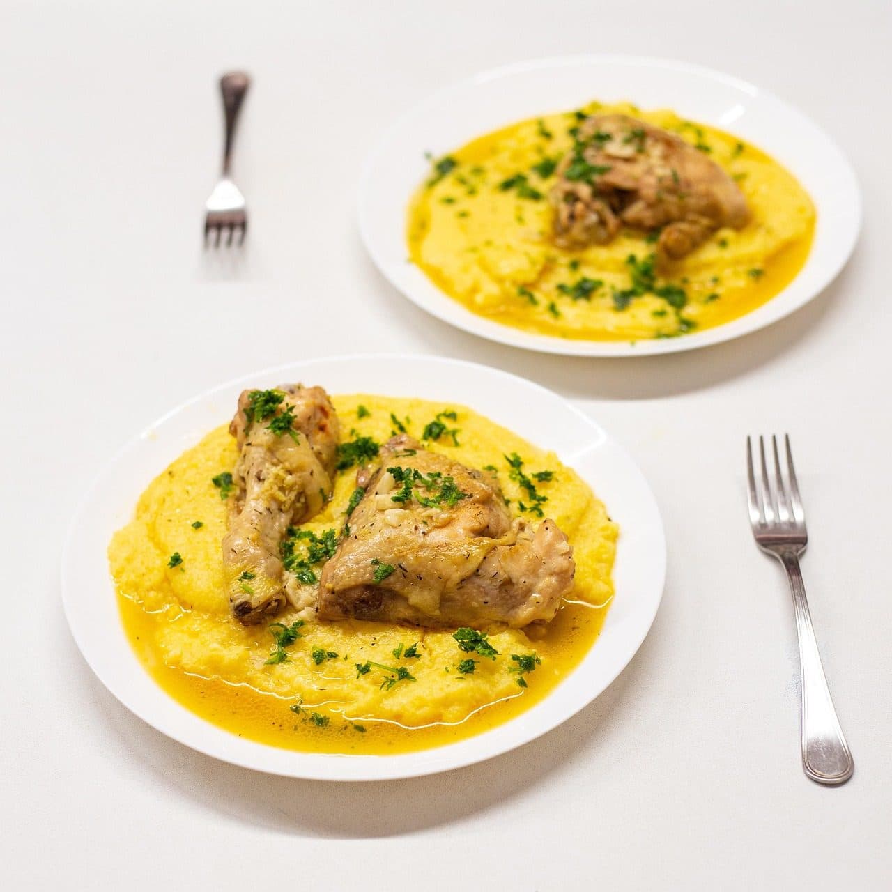 Prato com frango e polenta servido à mesa com garfo