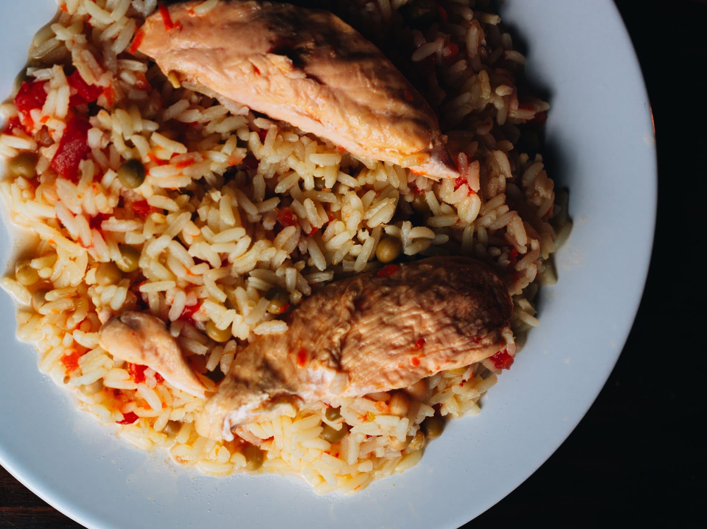 Prato de frango com arroz servido em prato branco, visto de cima
