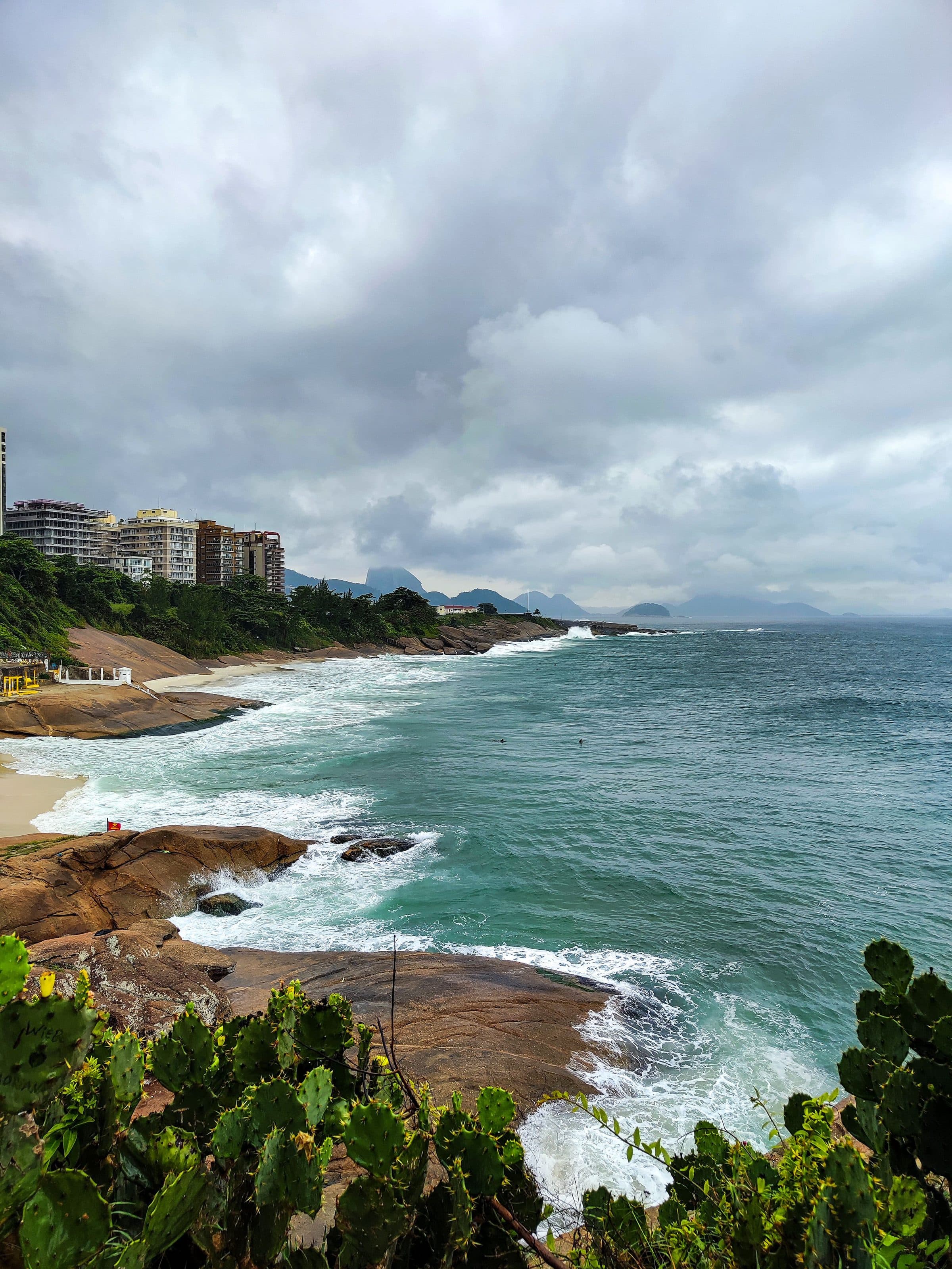 Vista de praia no Rio de Janeiro com costa rochosa e ondas do mar