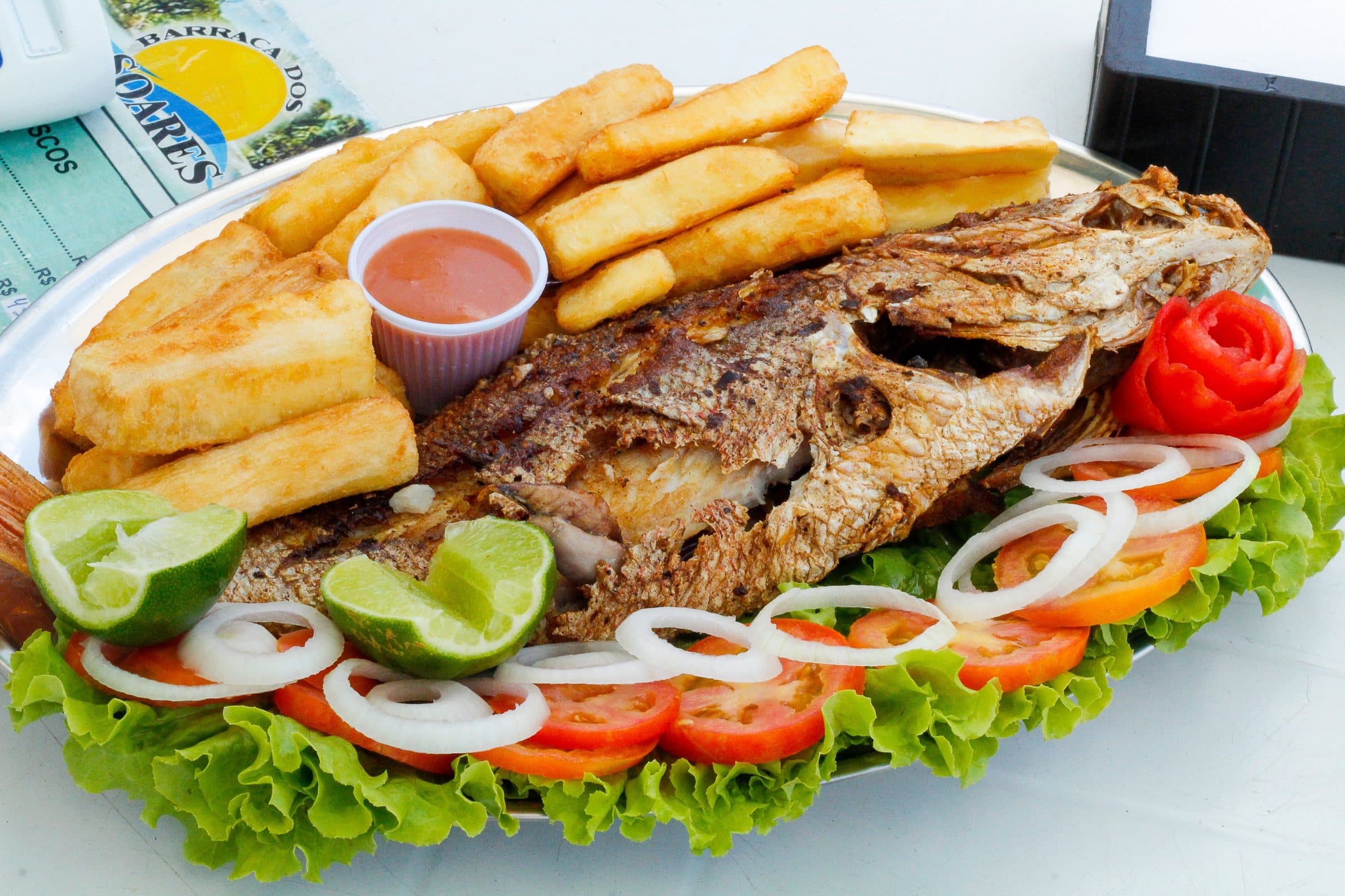Peixe grelhado servido com batatas fritas e vegetais frescos