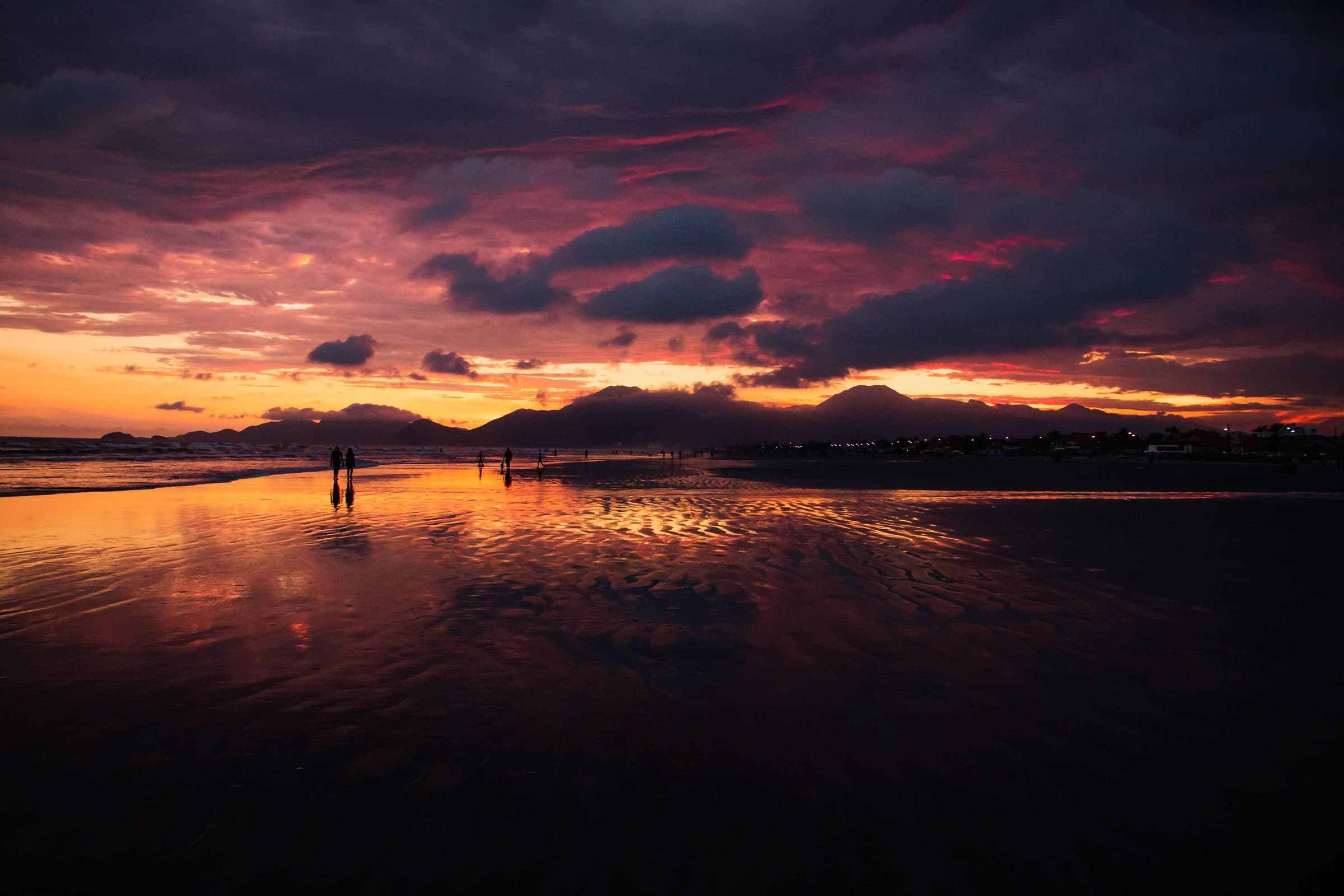 Pôr do sol na praia de Peruíbe com reflexos coloridos sobre a água do mar