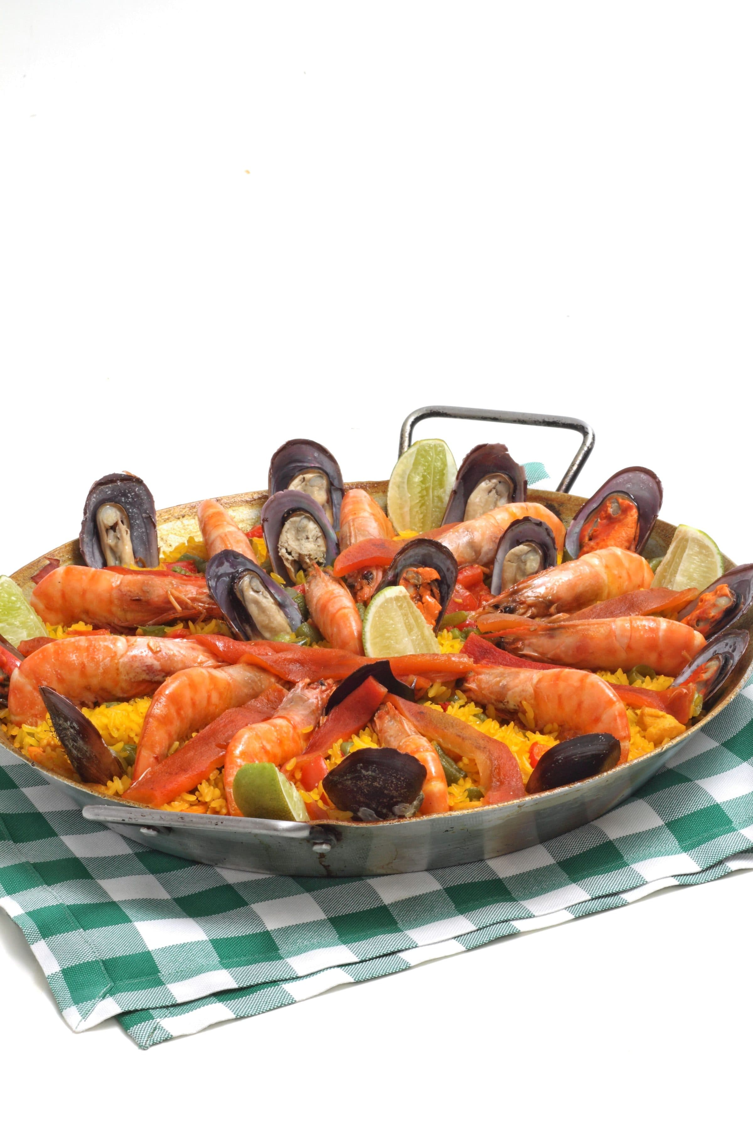 Paella de frutos do mar decorada com camarões e mexilhões sobre fundo branco