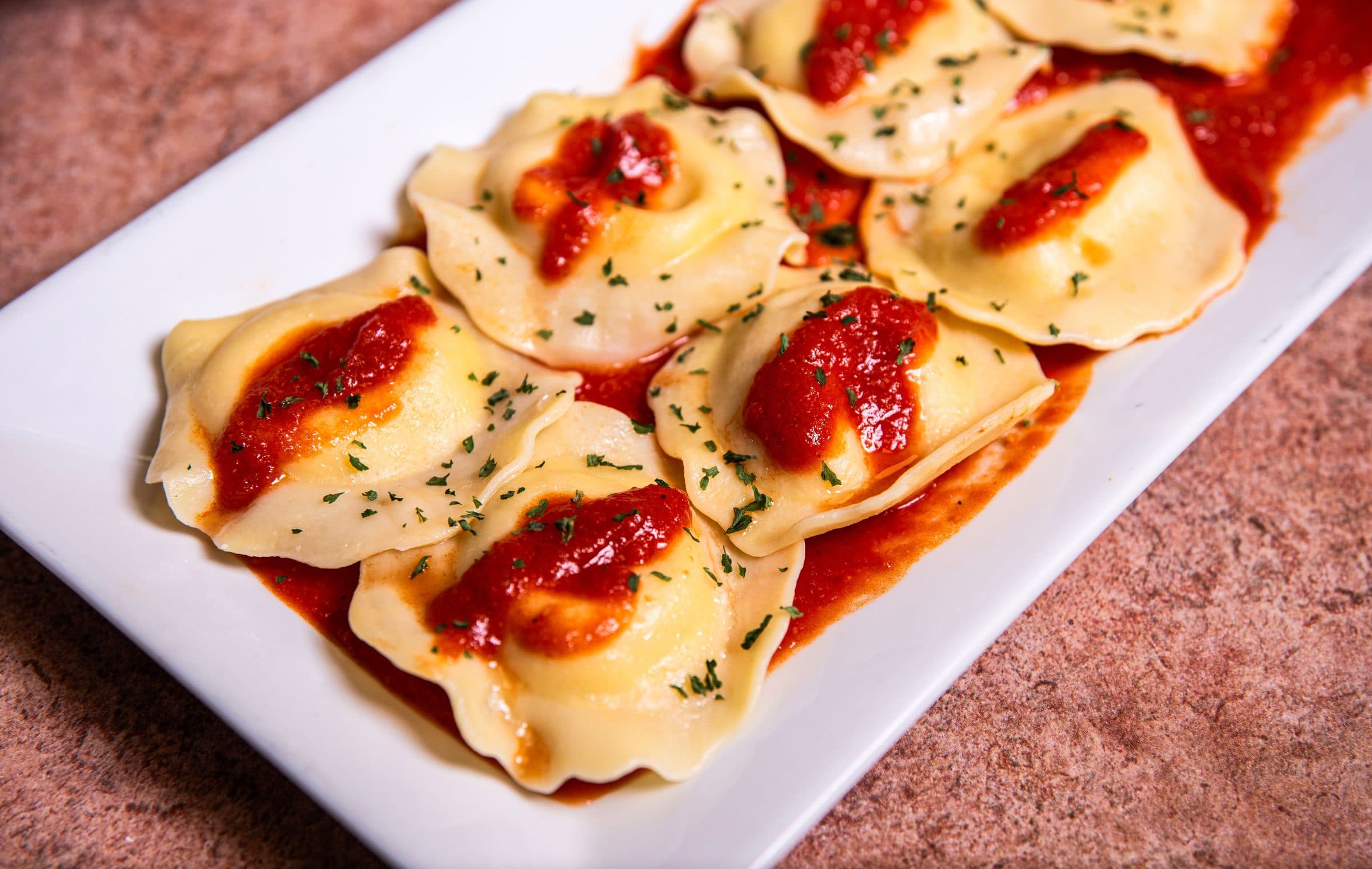Ravióli ao molho de tomate salpicado com ervas em um prato branco