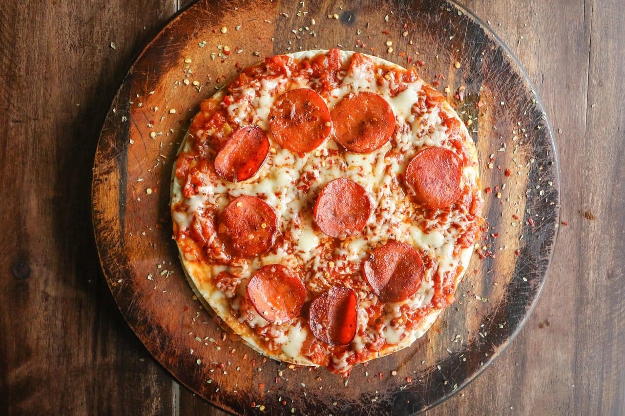 Pizza de pepperoni com queijo mussarela, massa fina e flocos de pimenta
