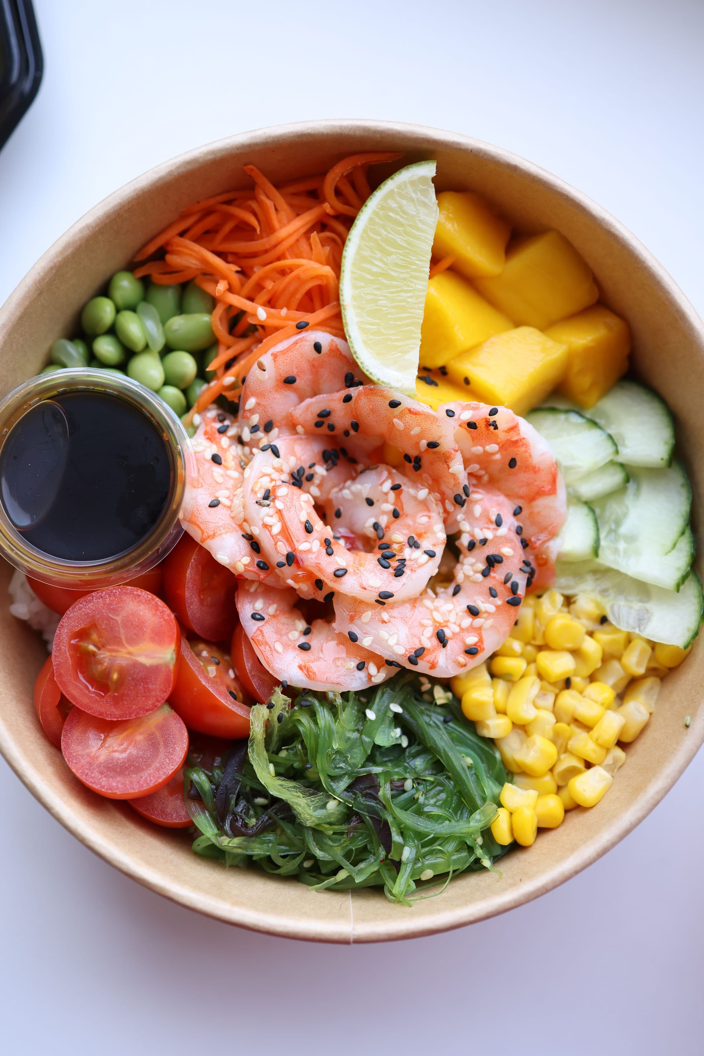 Tigela de poke servida com camarões, pedaços de manga e vegetais