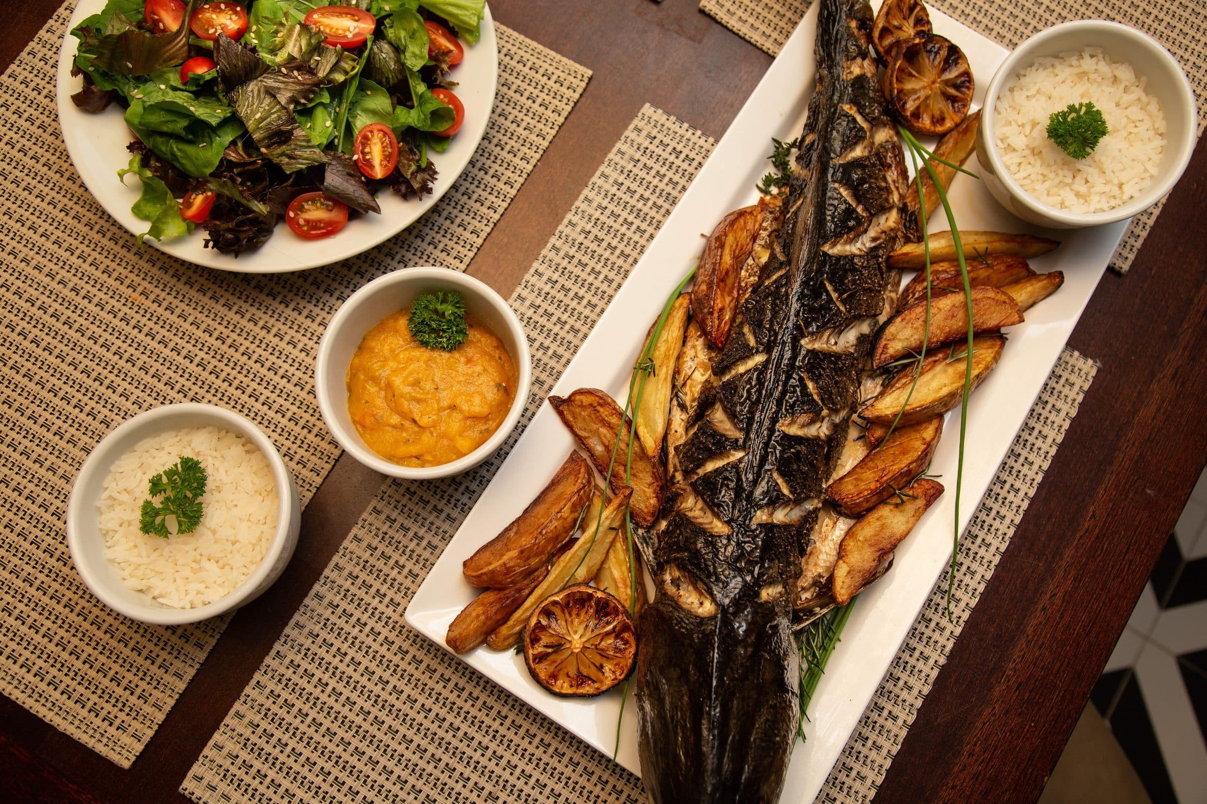 Prato de peixe servido com arroz, salada e batatas assadas