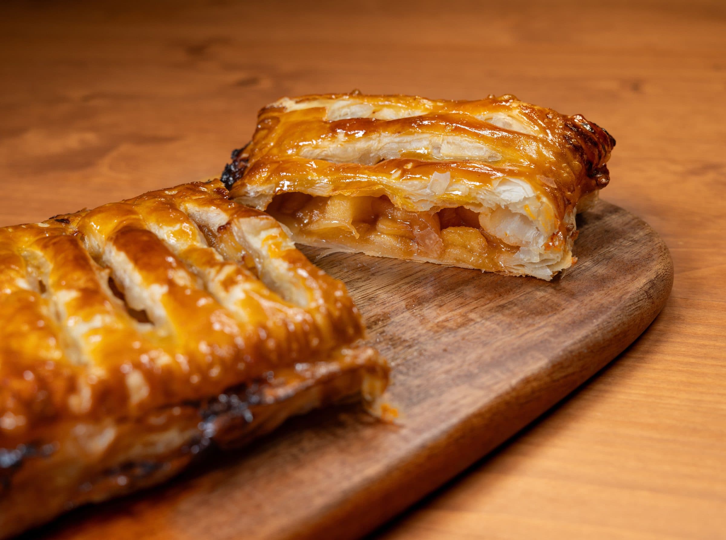 Strudel de maçã assado com massa folhada dourada sobre uma tábua de madeira
