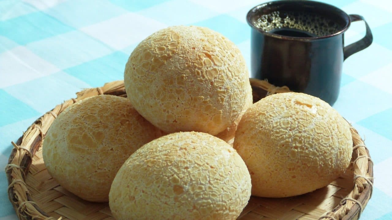 Mesa servida com café, pães, queijo e bolo