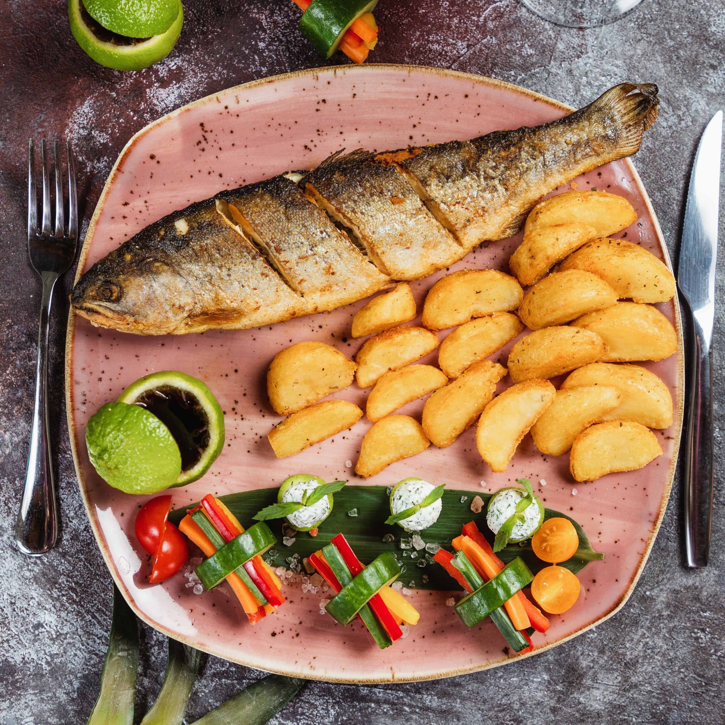 Prato com peixe grelhado acompanhado de batatas rústicas e legumes